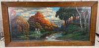 Full view of the framed print showing the river scene with two swans, autumn-colored trees, and the wooden frame.