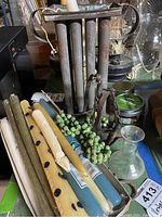 Photo showing assortment of wax candles in blue, cream, green, and brown colors with decorative details next to the vintage metal candle molder and green bead garland.