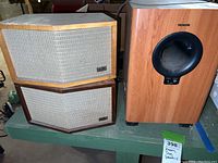 Pair of JansZen Electrostatic Model 65 speakers stacked on left and the TEAC LSR-200 speaker on right, sitting on a green surface in a basement environment.