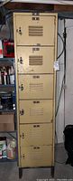 Full upright metal locker unit with six lockers stacked vertically in basement setting.