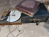 Wooden Edison manual crank record player beside black electric turntable and binder