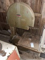 Front view of the Walker-Turner bandsaw showing the metal blade guard, cutting table with surface wear, and attached electrical cord.