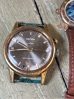 Gold-tone Vulcain Cricket wristwatch with black dial and green leather strap