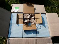 Open cardboard case showing 6 smaller blue boxes packed inside, each box containing 4 wrapped wine glasses.