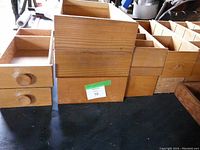 Various vintage wooden drawers of different sizes, some with multiple compartments and some with knobs.