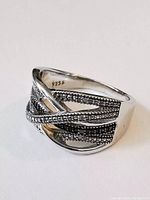 Front and side view of the intertwined sterling silver ring showing polished and textured bands with diamond chip accents, marked 925 inside.