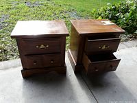 Pair of small wood and pressboard nightstands, one drawer open showing wear on tops.