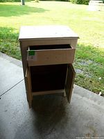 Front view of the wooden shop cabinet showing partially open drawer and double doors below.