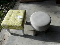 Two footstools shown side by side in sunlight on concrete floor. Square footstool is green and white patterned with white legs, round footstool is grey with wooden legs.