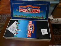 Complete Deluxe Anniversary Edition Monopoly game cross open box showing logo on lid and game board inside with manual