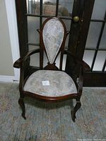 Front view showing the upholstered fabric with muted floral pattern and carved wooden frame with curved arms.