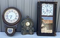 Collection of three antique clocks including two wooden wall clocks and one ornate metal clock, showing overall size and condition.