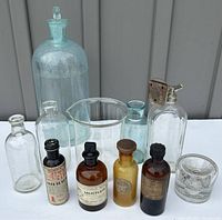 Full view of all antique glass bottles including medicine bottles and labware.
