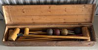 Original wooden box open showing croquet mallets and croquet balls inside.