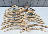 Collection of 22 wooden advertising hangers laid out, showing printed business names and addresses.