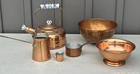 Wide group photo of 6 copperwares including teapot, bowls, pitcher, measuring cup, and small cup.