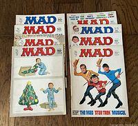 Eight vintage 1970s Mad Magazines displayed in two stacks, showing a mix of cover art including humorous and satirical images.
