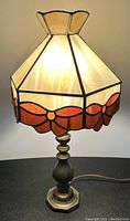 Full front view of the lamp lit showing caramel stained glass shade with amber glass bow border and brass base