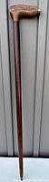 Full length view of wooden walking stick showing straight dark brown shaft and lighter L-shaped handle