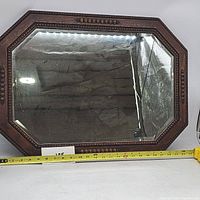 Full front view of the antique octagonal oak mirror with measuring tape showing width approximately 25 inches.