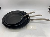 Three nested Calphalon fry pans with stainless steel handles shown from top