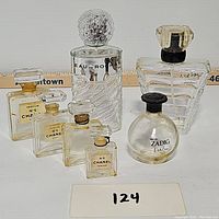 Front view of seven empty designer perfume bottles, four Chanel No. 5 bottles of various sizes, Eau Rochas, Lancôme Trésor, Zadig