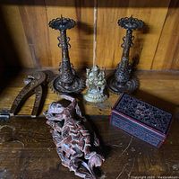 Photo showing the entire lot on a wooden surface, including the brass Ganesha statue, two metal candle holders, carved wooden figurine, wooden nutcracker, and decorative box.
