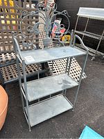 Front view of the vintage folding metal plant stand with three shelves and decorative back.