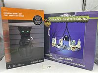 Two boxes of Halloween decorations: Ashland Animated Scary Cat and Haunted Chandelier with Sound showing front packaging and product details.