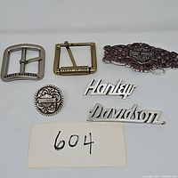 Overview of five Harley-Davidson branded buckles and accessories arranged on white background.
