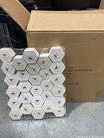 Large cardboard box open showing multiple hexagon-shaped white jewelry boxes stacked inside.