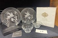 Lot overview showing two clear crystal plates with hummingbird design and two crystal candleholders, along with original box and booklet.