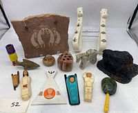 Lot laid out showing Kokopelli stone wall hanging, ceramic wall hangings, marble animals, plastic toys, and carved figures.