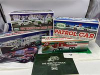 Showing three Hess toy cars in original boxes alongside 7 Eleven toy race car carrier box and Hess Toy Truck catalog booklet with Hess bags.