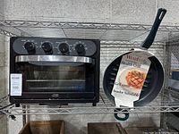 Mini oven and frying pan displayed side by side on a metal shelf