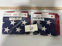 Pair of new US flags folded and sealed in plastic packaging with measurements shown by ruler.