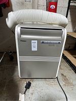 Front view of Haier portable air conditioner showing exhaust hose and power cord on concrete floor.