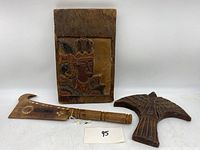 Photo showing the Indonesian carved panel with a colored human figure carving, the South Pacific wooden item with handle, and the hand carved wooden eagle figurine together.