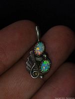 Close-up photo of the antique sterling silver pendant with two oval opal stones showing fire and color play.