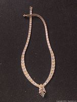 Full view of chunky, three-tone sterling silver necklace with woven design, laid flat on black background.