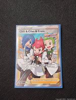 Photo of a holographic full art Pokémon Trainer card featuring Chili, Cilan, and Cress from the Fusion Strike expansion set.