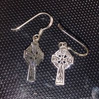 Pair of sterling silver Celtic cross earrings with detailed knotwork set on a textured black background, hooks upsidedown.