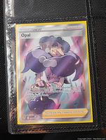 Full Art Holo Foil Opal Trainer Pokemon card in black binder sleeve showing card front with artwork and holo foil effect.