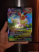 Hand holding oversized Flareon VMAX holographic foil Pokémon card showcasing front with vibrant colors and effects.