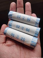 Sealed paper rolls of 2022 Canadian 5-cent coins showing value $2 and 5c markings, held in hand.