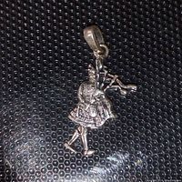 Close-up photo of the sterling silver Scottish piper pendant showing detailed figure and attached bail.