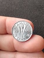 Reverse side of the 1945 Canadian V nickel coin showing the torch, maple leaves, year, and denomination.