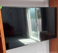 Sony 58" TV mounted on wall showing blank screen with room reflection