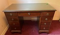 Front view of the antique wooden desk showing the glass top and all drawers
