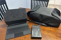 Black UROS USB antitheft waterproof backpack, tablet keyboard, and USB optical mouse on wooden table